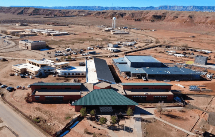 Aerial view of a school campus surrounded by a rugged desert landscape and red rock mesas.