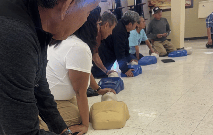 School staff members practice CPR on training mannequins during a first aid certification session.