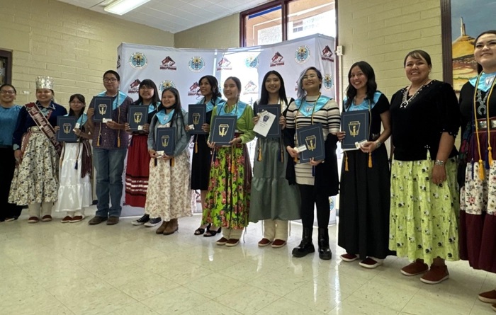 The nine students inducted into the National Honor Society standing in a line holding their awards.