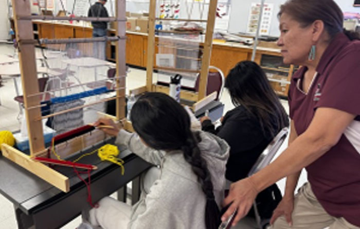 Two students learning to weave while Mrs. Virginia Jones assisted.