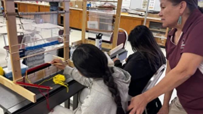 Two students learning to weave while Mrs. Virginia Jones assisted.
